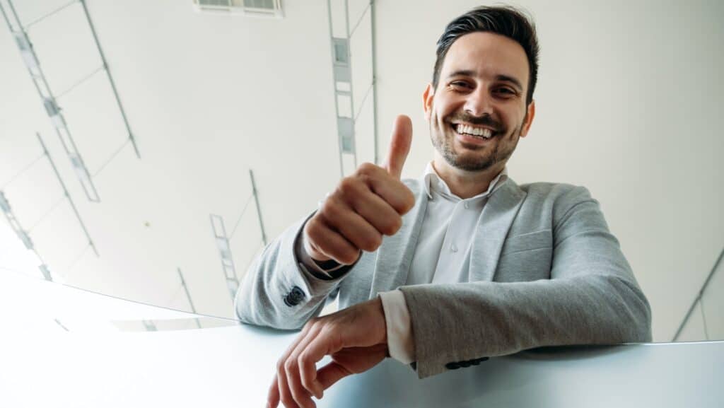 Happy business man shows thumb up sign gesture